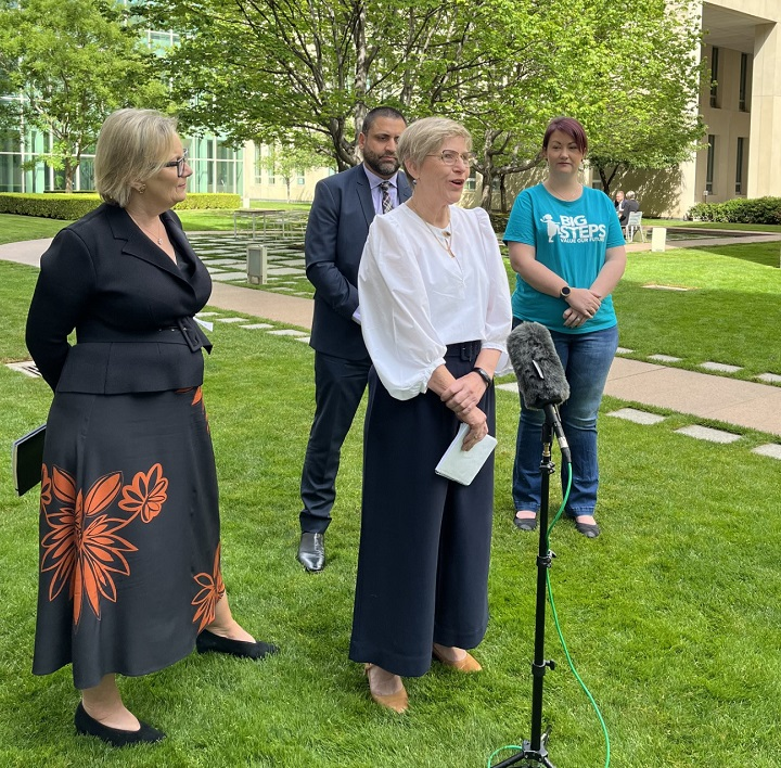 Woman giving speech outside with Big Steps professionals are in the background